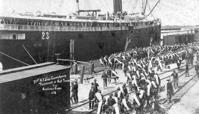 A black and white photo taken in 1898 of soldiers loading a ship at Port Tampa during the Spanish American War.